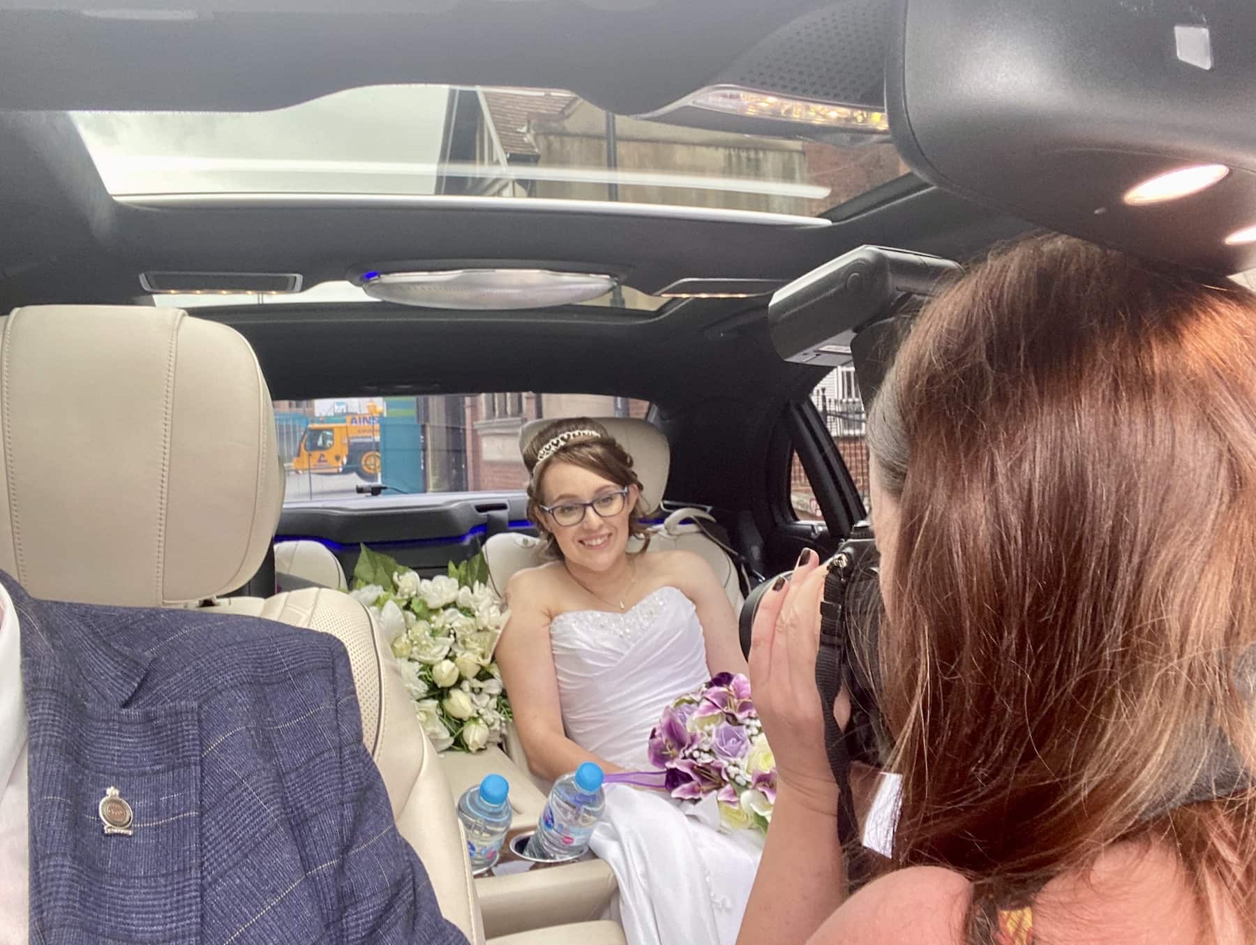 Bride getting photographed whilst sat in our Mercedes S Class Wedding Car in Derby