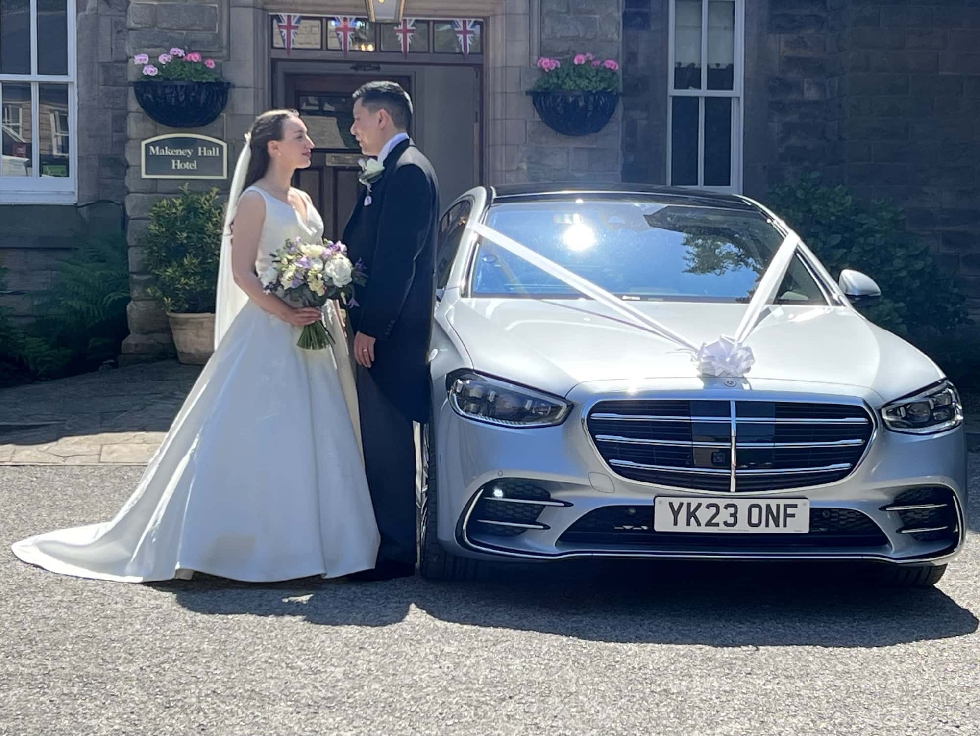Bride andf Groom standing by A52 Executiev Cars Silver Mercedes S Class Wedding Car in Derby