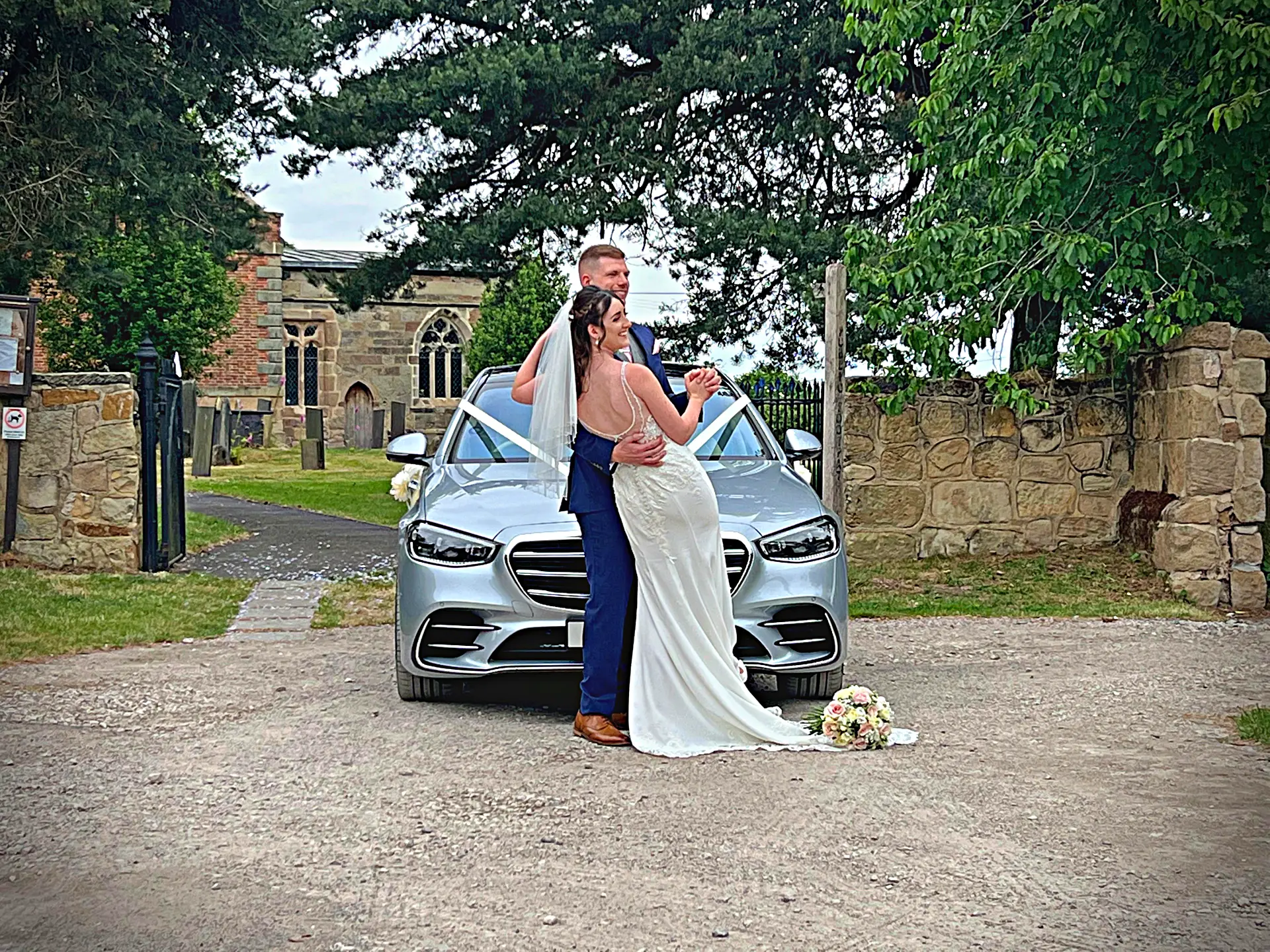 Mercedes S-Class wedding car decorated with ribbons for a Derby wedding and bride and groom posing in front