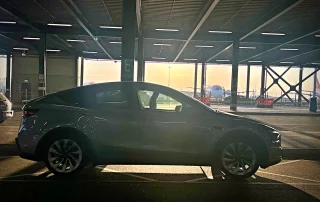 derby-luton-airport-chauffeur-transfer-tesla-model-y-sunset-a52-executive-cars Tesla Model Y executive chauffeur vehicle at London Luton Airport during a Derby to Luton Airport transfer by A52 Executive Cars