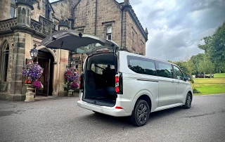 Executive tour vehicle outside a historic Derbyshire country house