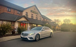 Mercedes S-Class executive chauffeur vehicle outside hotel entrance