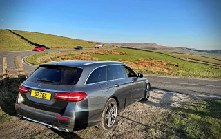 Luxury chauffeur vehicle on a scenic Peak District road near Snake Pass